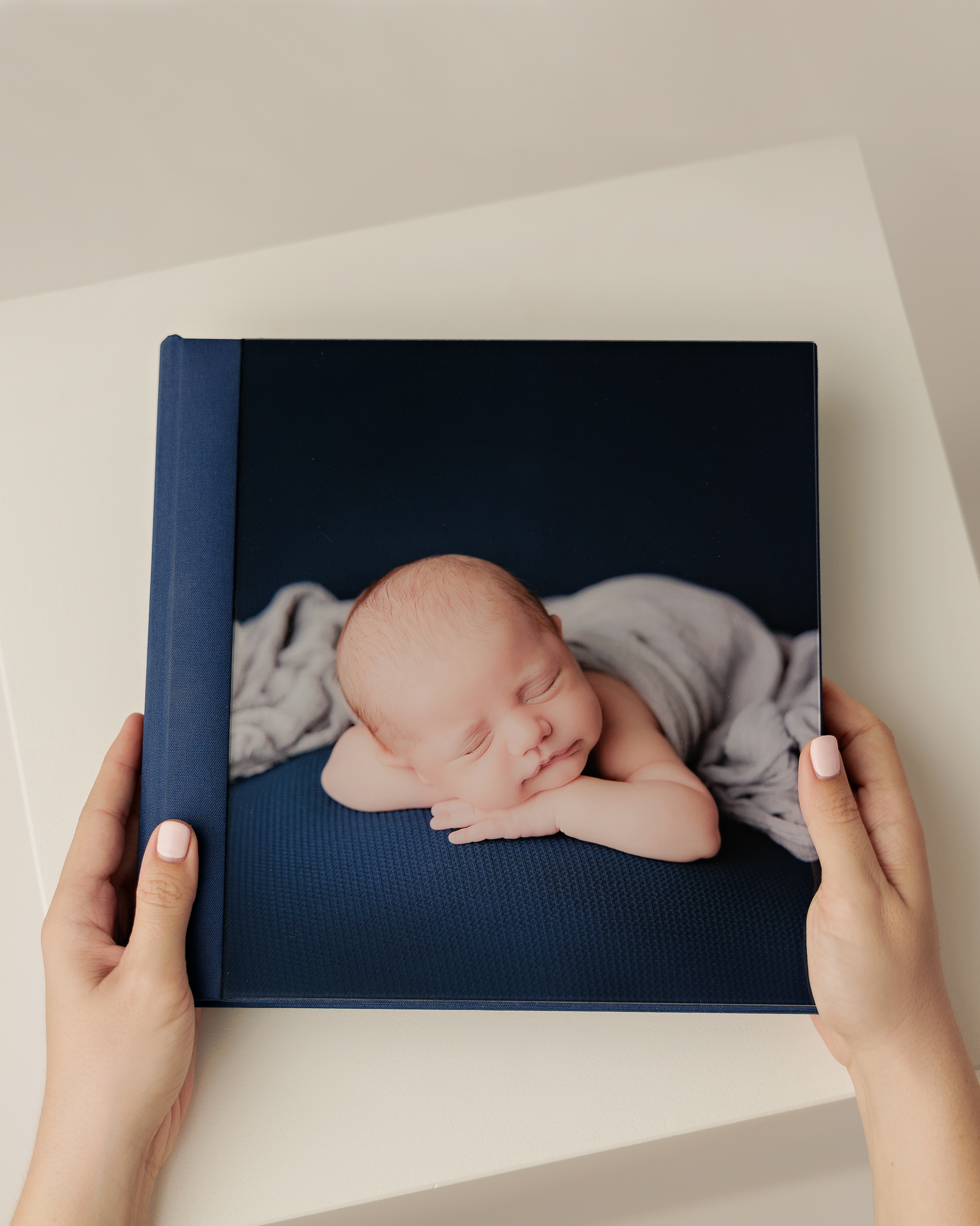 hands holding a premium luxury acrylic album of a newborn photography calgary