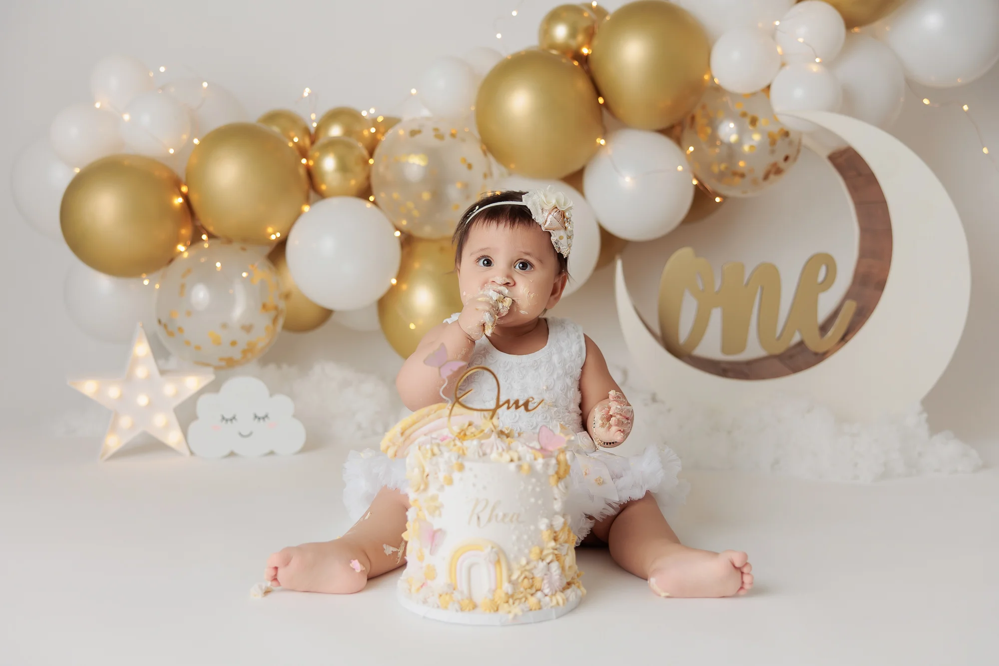 cake smash photography with gold and white balloon garland