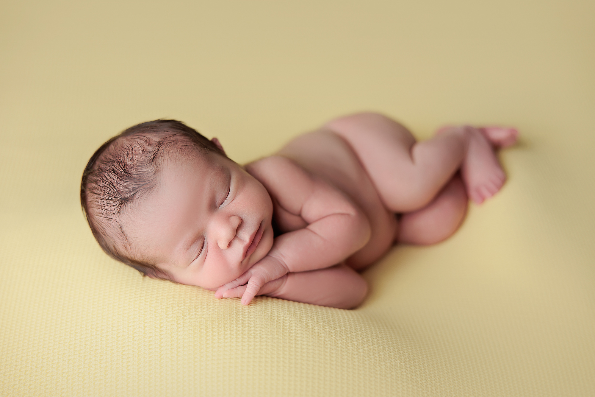 newborn baby boy sleeping on a yellow blanket