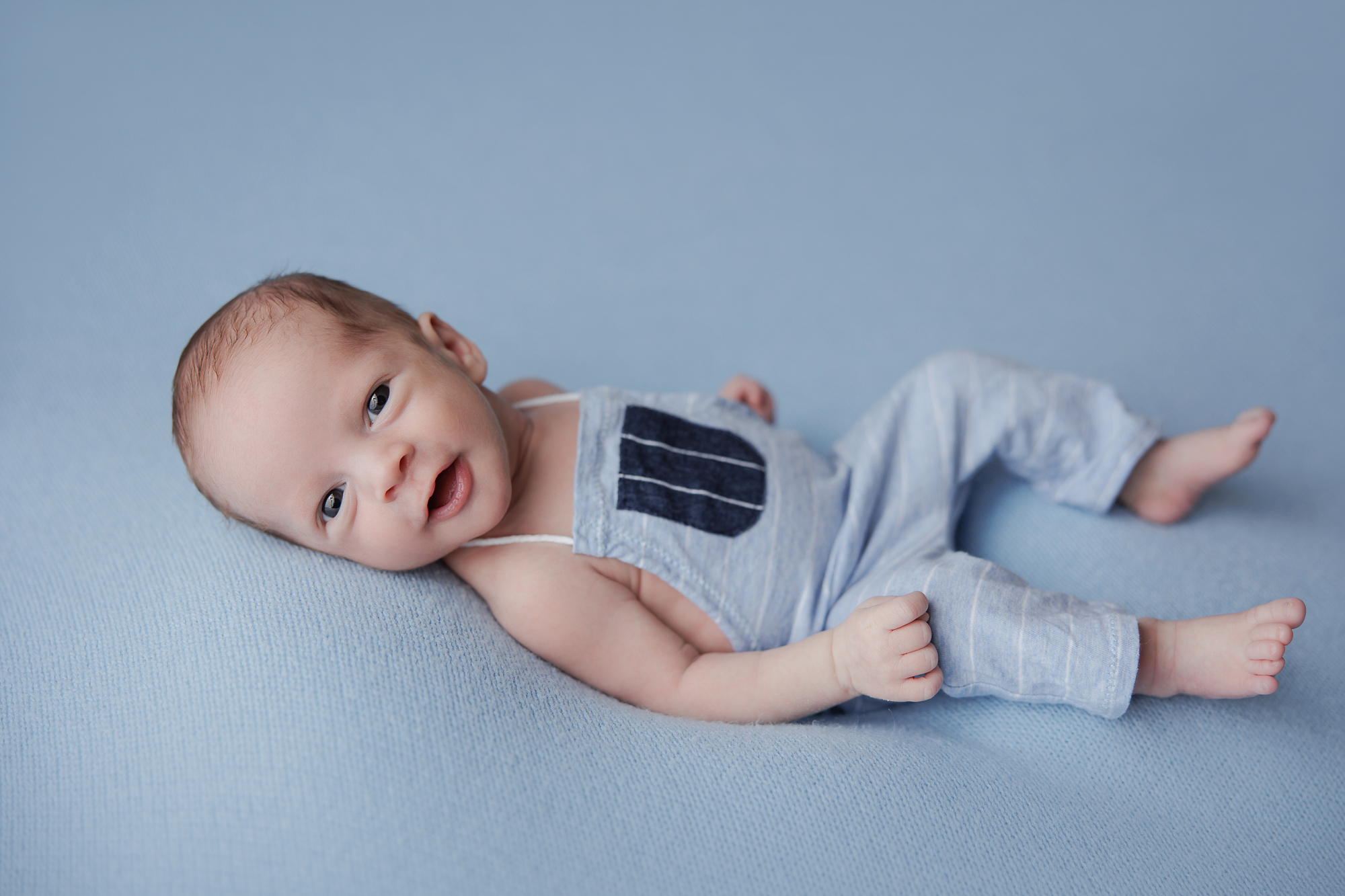 newborn photography baby boy in blue staring at the camera