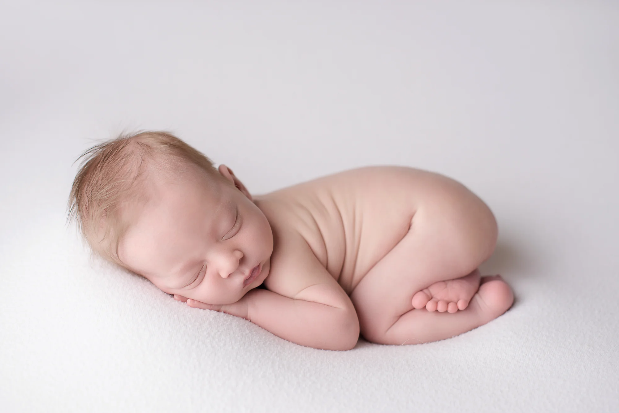 newborn photography naked baby sleeping on white blanket