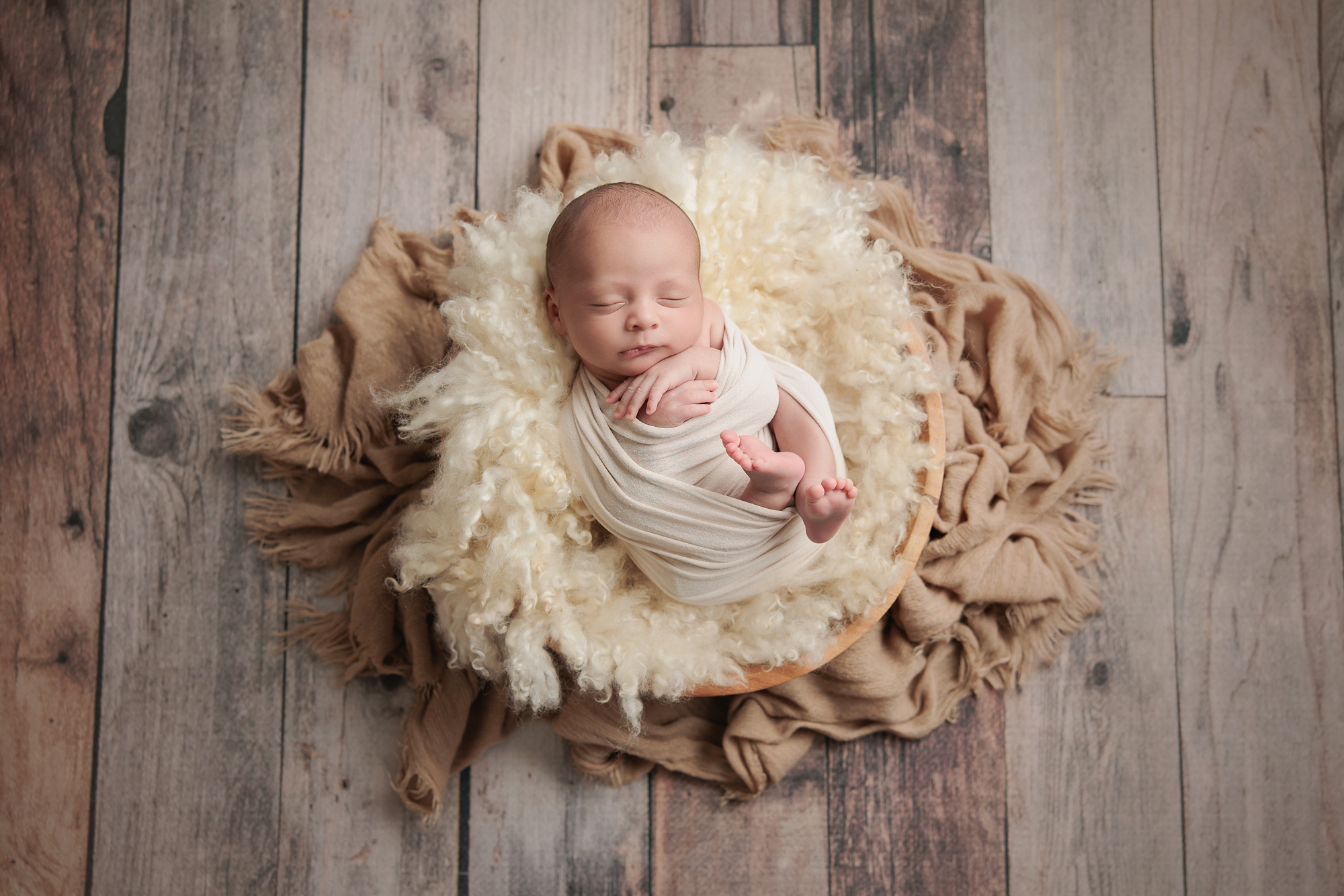 Mother feeding her newborn in a cozy studio chair before posed portraits begin