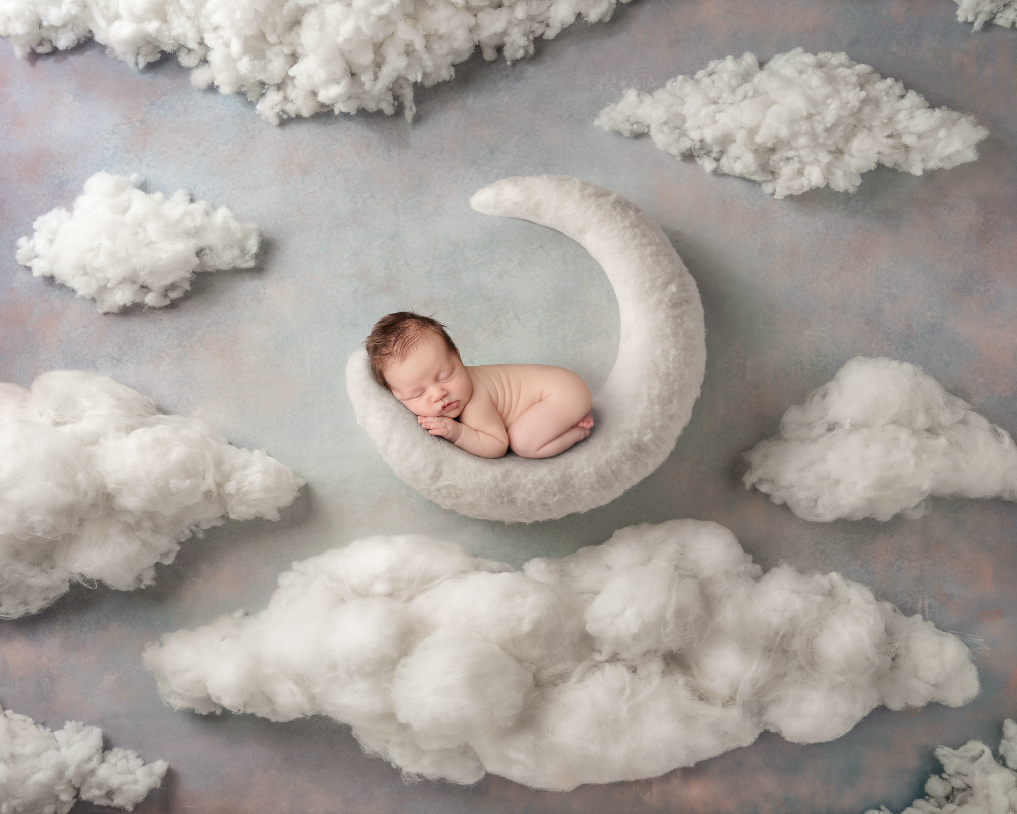 Newborn held upright against a parent's chest during a soothing break in a warm photography studio