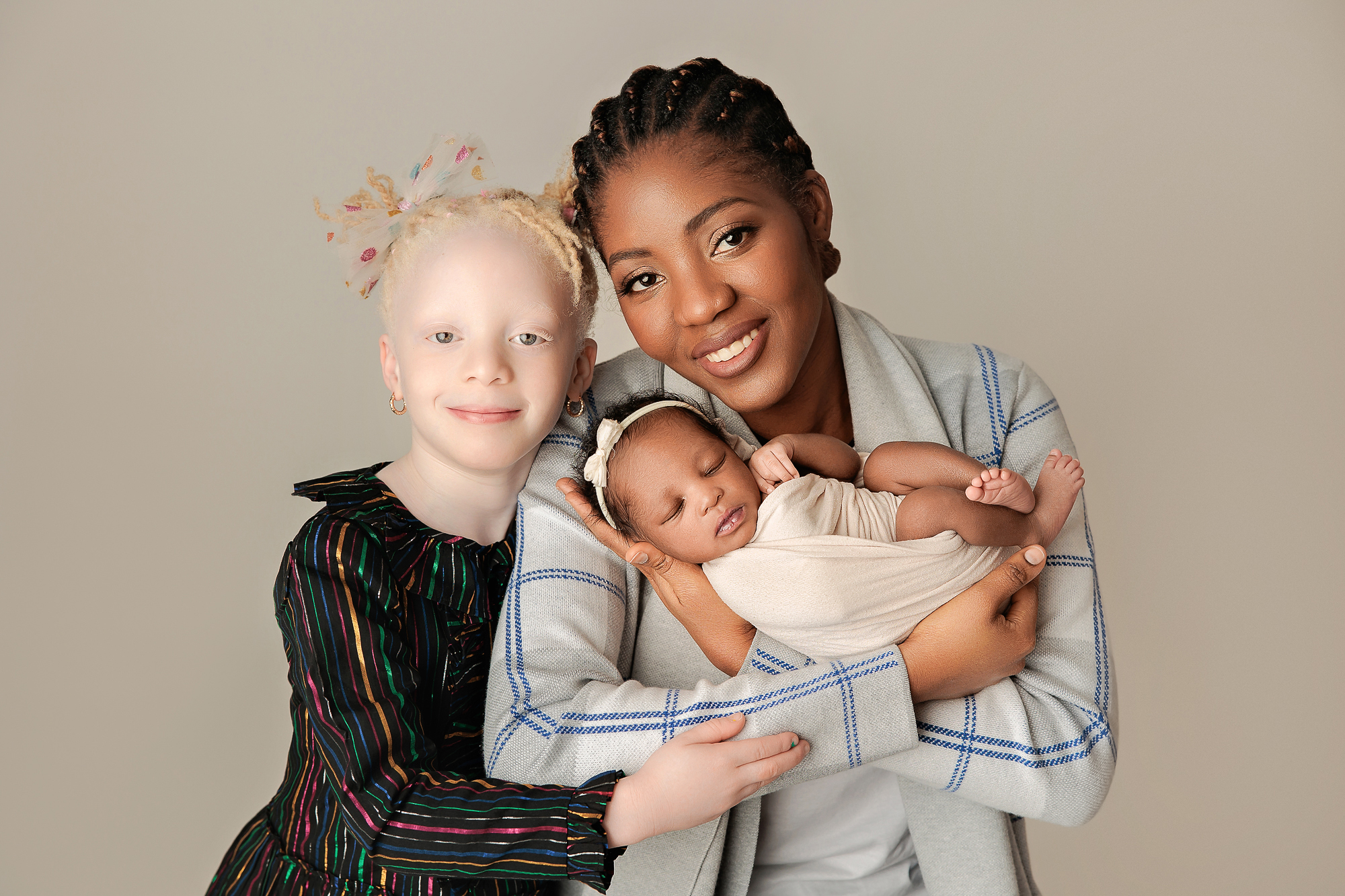 Newborn baby posed on neutral blanket beside photographer's editing workspace after a session