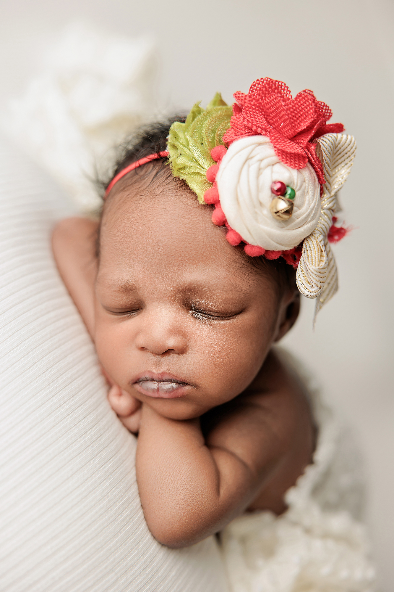 Close-up of newborn hands and tiny fingers resting on textured cream fabric