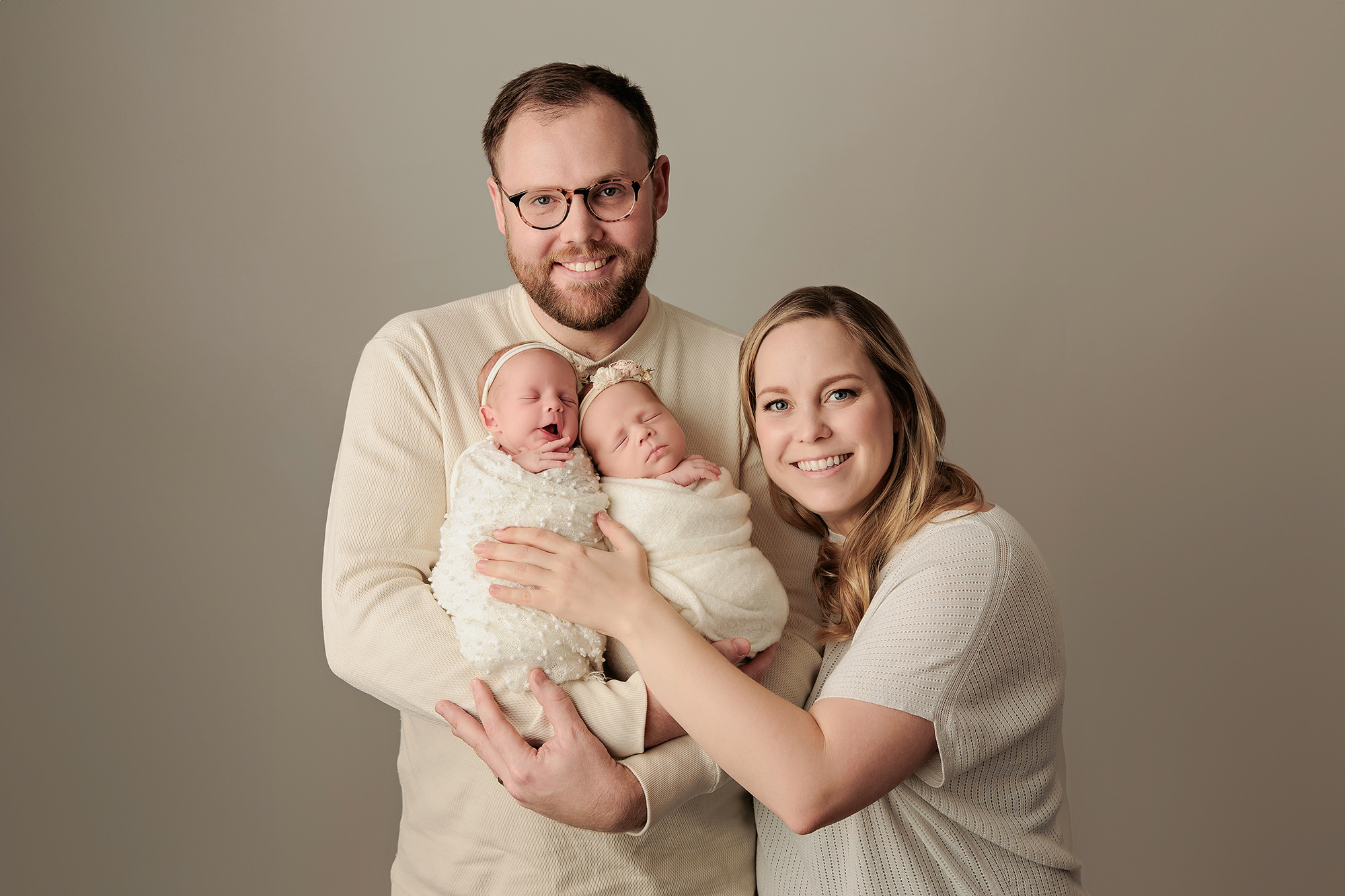 Mother cradling newborn against soft neutral backdrop in Calgary photography studio