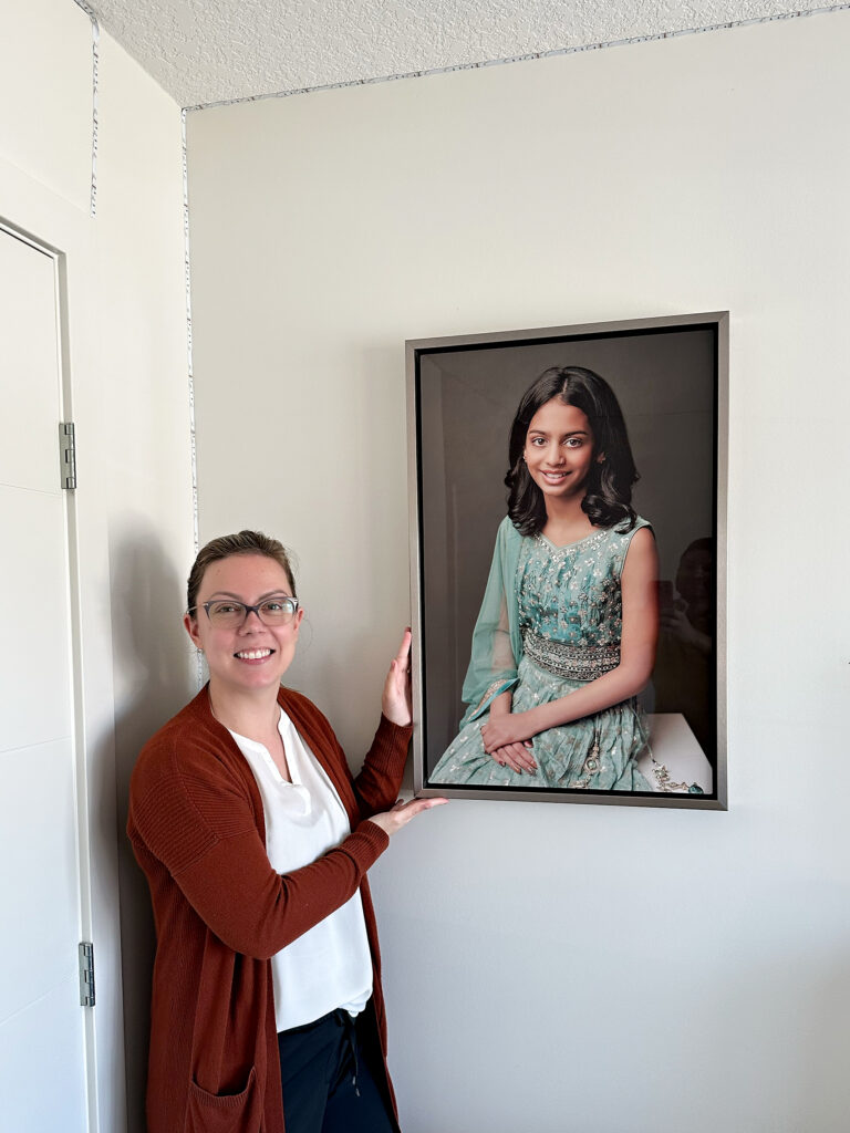 Amanda Dams next to a installed wall art at client's home