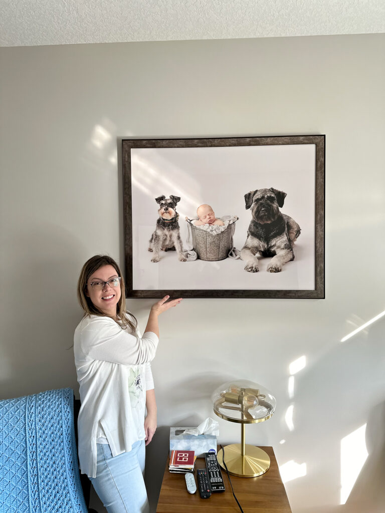 Amanda Dams showing a wall art with baby and dogs