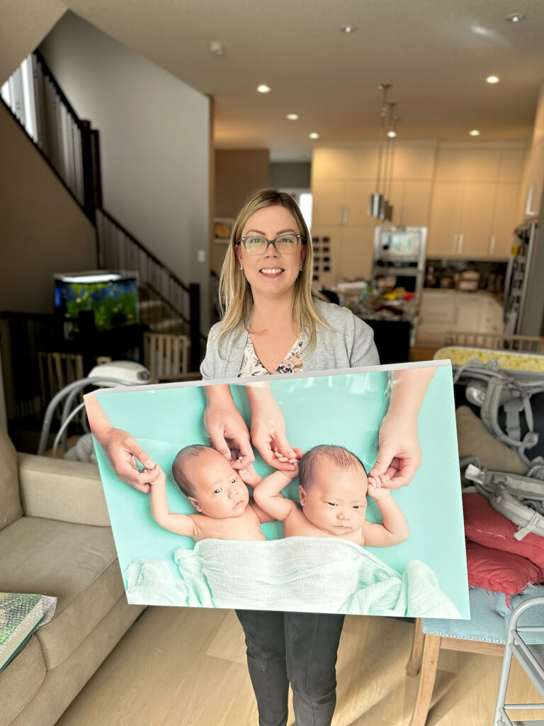 Amanda Dams holding a newborn twins wall art in Calgary