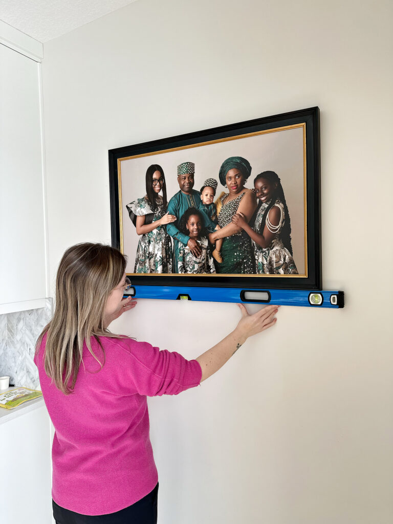 Amanda Dams installing wall art at client's home in Calgary