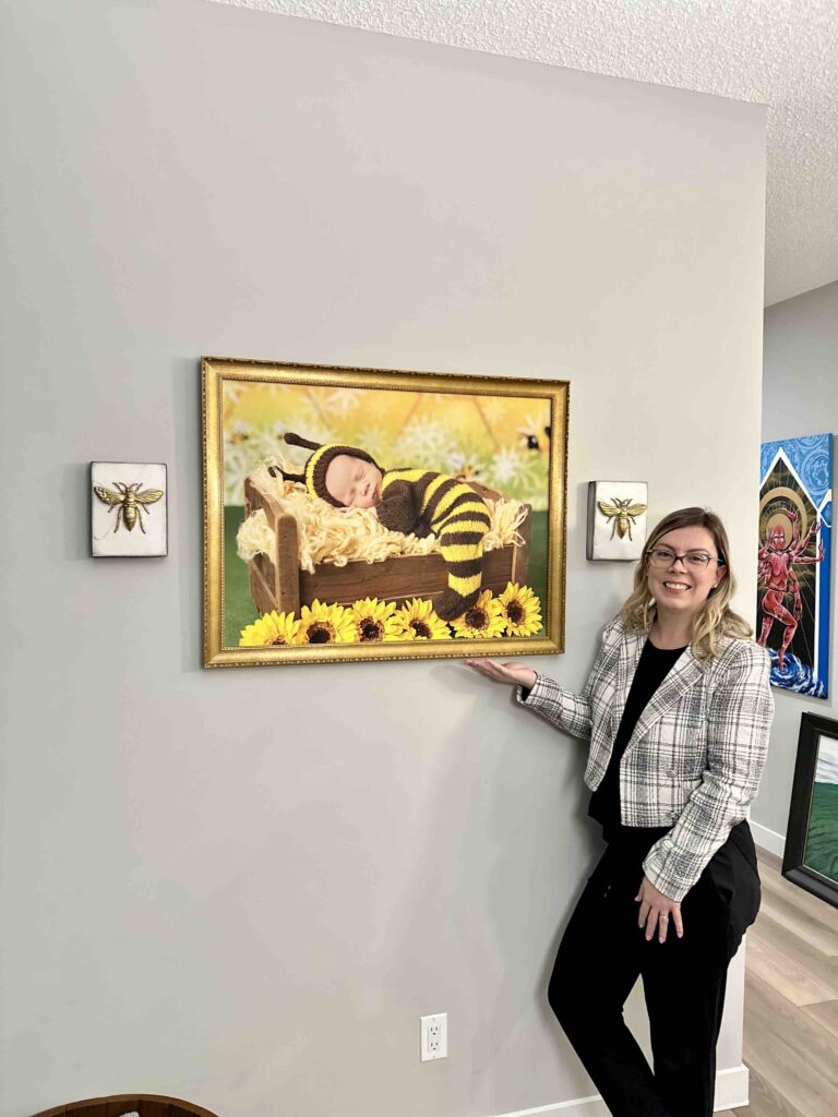Amanda Dams showing wall art of a newborn photo session bee theme