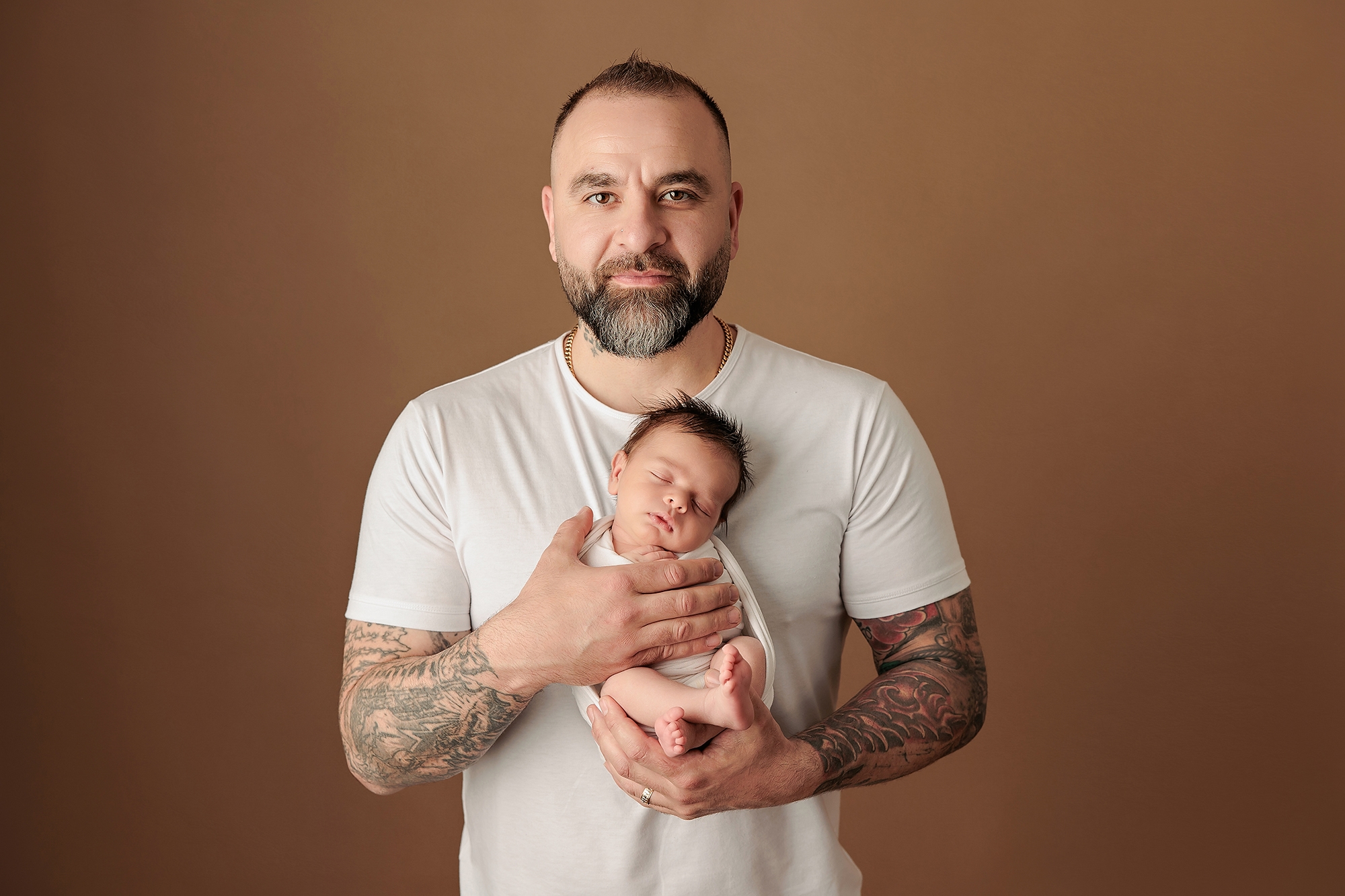 Mother cradling her newborn twins in neutral tones during an in-studio family portrait